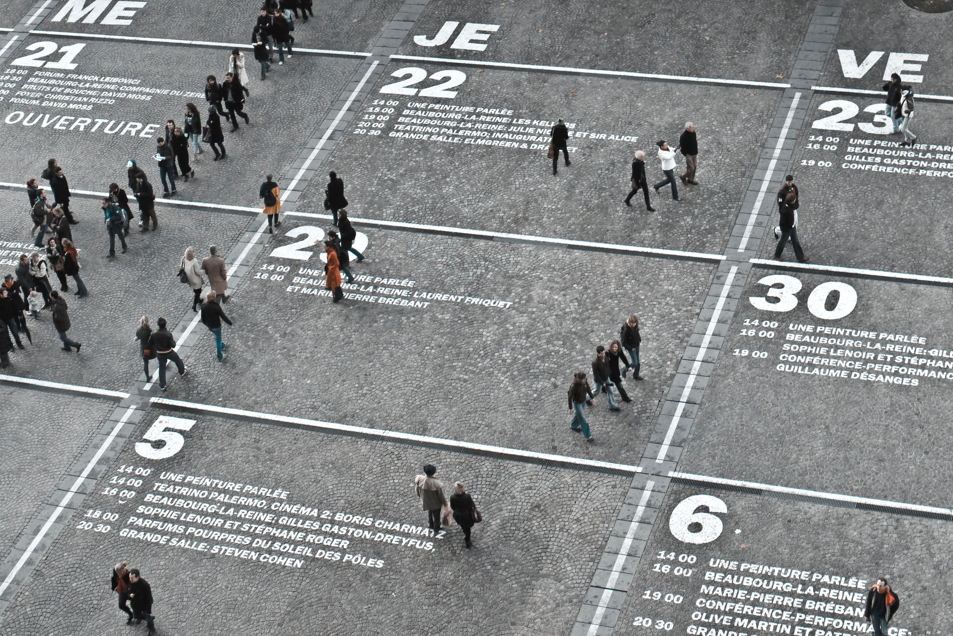 A painted schedule on the ground with people walking over it.