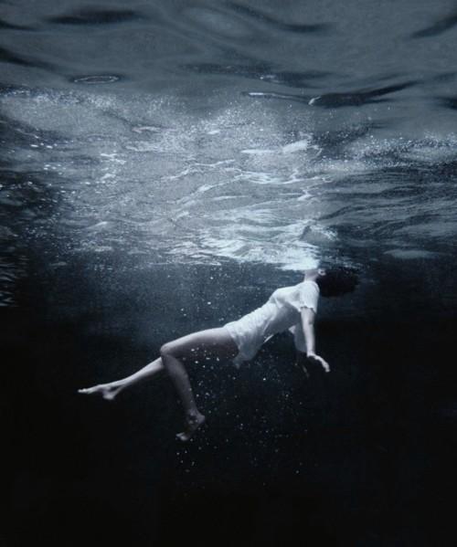 Woman in dark deep water falling down.