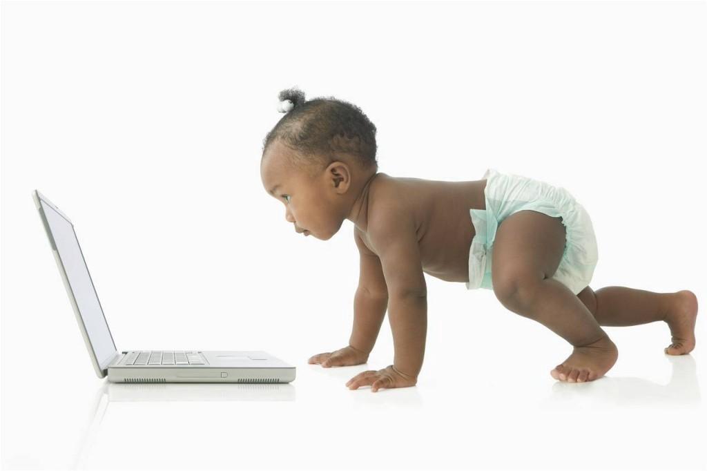 Cute baby in a diaper looking at a computer.