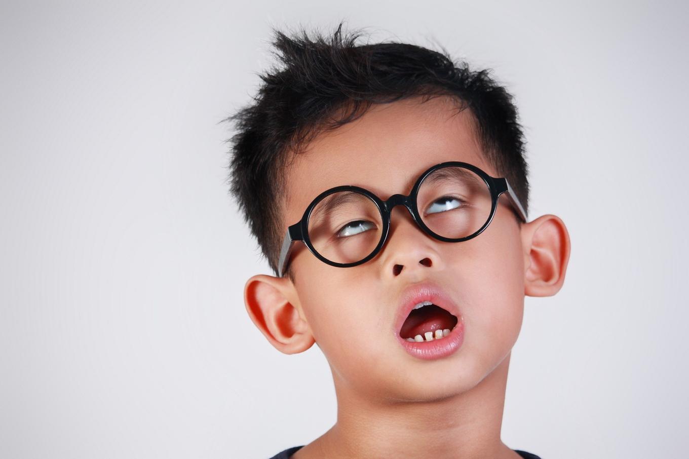 Little kid with round glasses looking very bored.